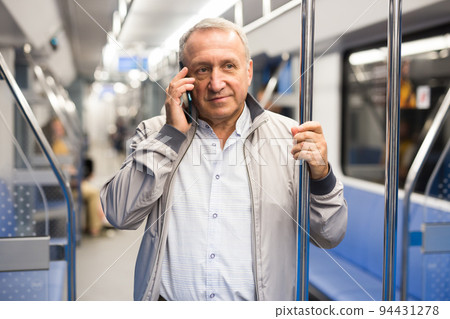 Smiling elderly man using mobile phone in subway car 94431278