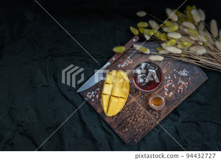 Glass of Iced tropical Mango smoothie mixed Espresso coffee served with Honey on the Wooden cutting board. Glass of Iced tropical Mango smoothie mixed Espresso coffee served with Honey on the Wooden cutting board. 94432727