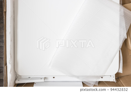 Opened box with furniture assembly parts and tools on the floor. Self assembling furniture at home concept. 94432832