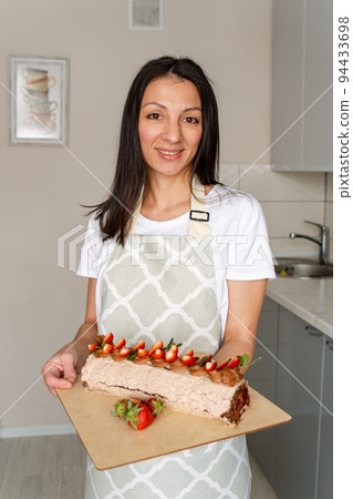 Professional confectioner decorating delicious cake with strawberry. Professional confectioner decorating delicious cake with strawberry. 94433698