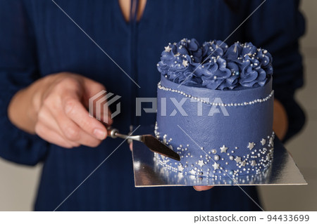 Confectioner is leveling cake with spatula and cake scraper. Confectioner is leveling cake with spatula and cake scraper. 94433699