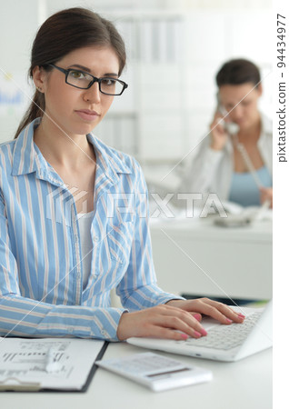 Portrait of a smiling beautiful business woman using a laptop. Portrait of a smiling beautiful business woman using a laptop. 94434977