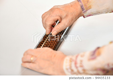 Senior woman's hand repelling the abacus Senior woman's hand repelling the abacus 94435133
