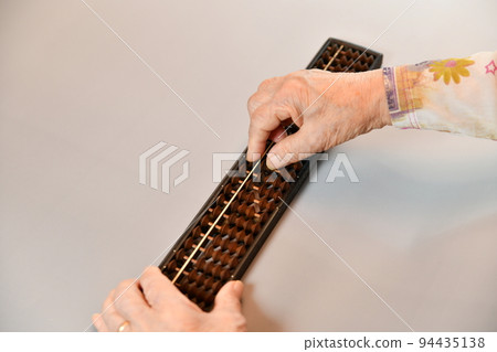 Senior woman's hand repelling the abacus Senior woman's hand repelling the abacus 94435138