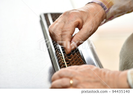 Senior woman's hand repelling the abacus Senior woman's hand repelling the abacus 94435140