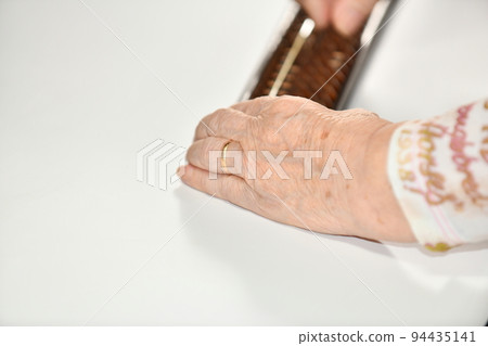 Senior woman's hand repelling the abacus Senior woman's hand repelling the abacus 94435141