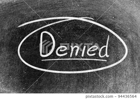 White chalk hand writing in word denied on blackboard background White chalk hand writing in word denied on blackboard background 94436564