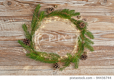 Christmas circle composition with fir tree branches and lighting garland on wooden background. Christmas frame, flat lay. Xmas greeting banner with copy space Christmas circle composition with fir tree branches and lighting garland on wooden background. Christmas frame, flat lay. Xmas greeting banner with copy space 94436744