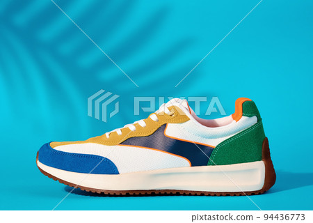 Stylish colorful shoes on blue background with plant shadows, Trendy sneakers, Stylish fashionable minimalism concept Stylish colorful shoes on blue background with plant shadows, Trendy sneakers, Stylish fashionable minimalism concept 94436773