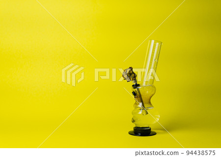 Marijuana bud and bong on yellow background, close up 94438575