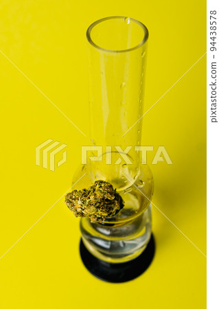 Marijuana bud and bong on yellow background, close up 94438578