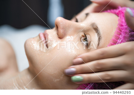 Cosmetologist applies cream on the skin of the client 94440293