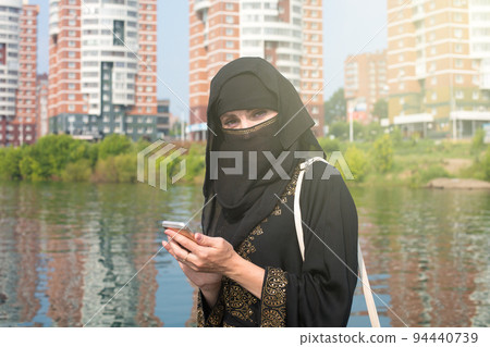 A Muslim woman in a national outfit walks around an unfamiliar European city after emigrating A Muslim woman in a national outfit walks around an unfamiliar European city after emigrating 94440739