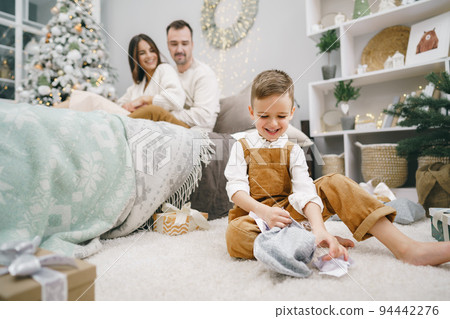 Happy little boy unwrapping his xmas gifts at home Happy little boy unwrapping his xmas gifts at home 94442276