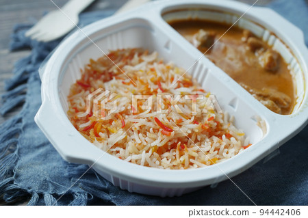 curry chicken and rice in a take away plastic packet on table curry chicken and rice in a take away plastic packet on table 94442406