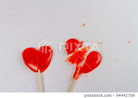 Top view two red lollipops on white background. Broken heart or unrequited love concept. Top view two red lollipops on white background. Broken heart or unrequited love concept. 94442789