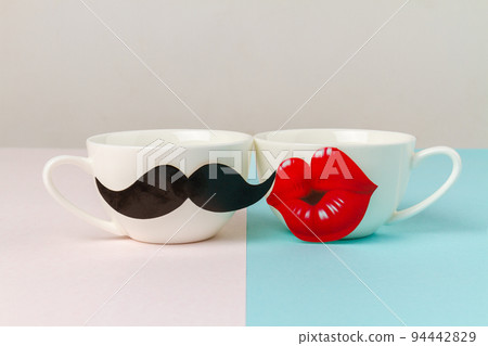 White cups decorated with moustache and lips. Love and relationship concept. White cups decorated with moustache and lips. Love and relationship concept. 94442829