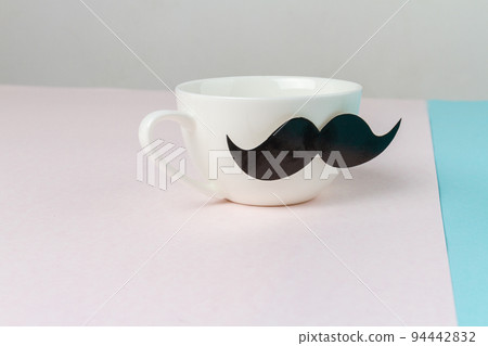 Close up of white ceramic cup with moustache. Concept of Fathers day. Close up of white ceramic cup with moustache. Concept of Fathers day. 94442832