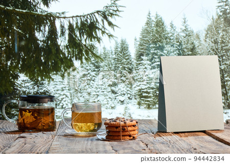 Homemade herbal or fruit tea. Glass pot, cup and sweets on wooden table over natural landscape background. Beauty, art, taste and traditions of countries Homemade herbal or fruit tea. Glass pot, cup and sweets on wooden table over natural landscape background. Beauty, art, taste and traditions of countries 94442834