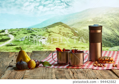 Homemade herbal or fruit tea. Glass pot, cup and sweets on wooden table over natural landscape background. Beauty, art, taste and traditions of countries 94442882