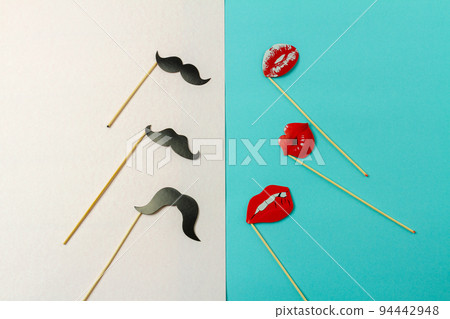 Paper moustaches and lips on wooden sticks. White and turquoise background. Paper moustaches and lips on wooden sticks. White and turquoise background. 94442948