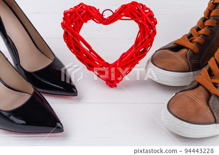 Close up footwear and red heart on white background. Mens and womens shoes. 94443228