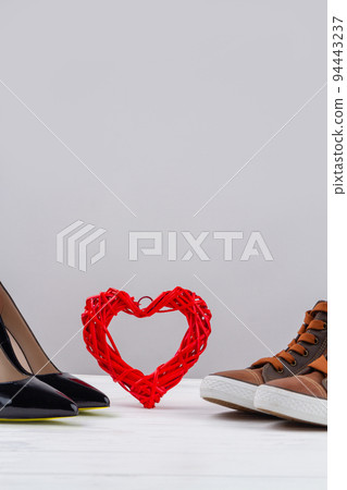 Still life of mens and womens shoes and red heart. Vertical shot copy space. 94443237