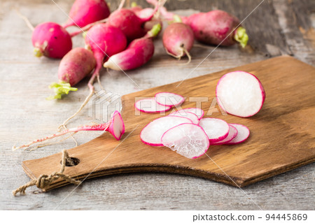 Fresh sliced radish on a cutting board on a wooden table. Vegetables for a vegetarian diet. Rustic style Fresh sliced radish on a cutting board on a wooden table. Vegetables for a vegetarian diet. Rustic style 94445869
