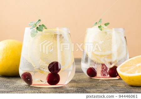 Summer refreshing cold cocktail with lemon and cherry - hard seltzer in glasses on the table. Close-up Summer refreshing cold cocktail with lemon and cherry - hard seltzer in glasses on the table. Close-up 94446061
