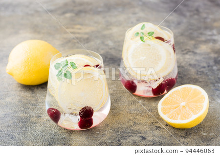 Summer refreshing cold cocktail with lemon, lemon balm and cherry - hard seltzer in glasses on the table Summer refreshing cold cocktail with lemon, lemon balm and cherry - hard seltzer in glasses on the table 94446063