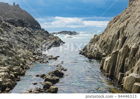 coastal cliffs formed by columnar basalt at low tide 94446313