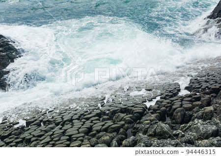 natural cobblestone causeway, formed by the ends of lava columns, descends into the sea surf natural cobblestone causeway, formed by the ends of lava columns, descends into the sea surf 94446315