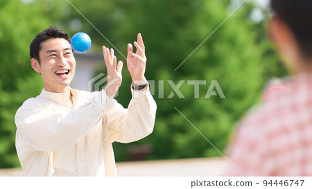Father playing catch with his son in the park 94446747