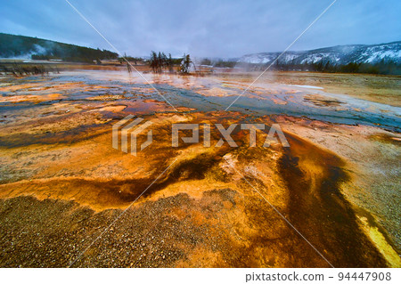Winter at Yellowstone basin with pools of alkaline water making colorful waves 94447908