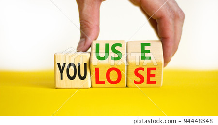 You use or lose it symbol. Concept words You use and You lose on wooden cubes. Businessman hand. Beautiful yellow table white background. Business and you use or lose it concept. Copy space. 94448348