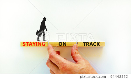 Staying on track symbol. Concept words Staying on track on wooden blocks on a beautiful white background. Businessman hand. Business, motivational and staying on track concept. Copy space. Staying on track symbol. Concept words Staying on track on wooden blocks on a beautiful white background. Businessman hand. Business, motivational and staying on track concept. Copy space. 94448352