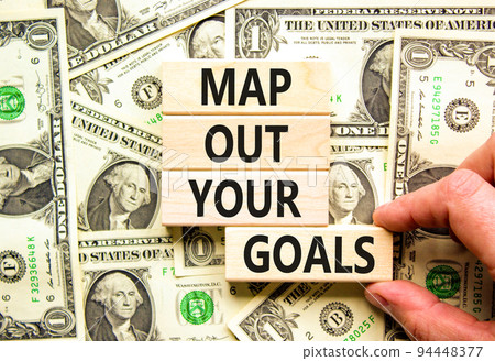 Support and map out your goals symbol. Concept words Map out your goals on wooden blocks on beautiful background from dollar bills. Businessman hand. Business, support and map out your goals concept 94448377