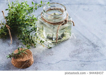 Thyme oil in a bottle, Thymus green leaves on gray background 94448437
