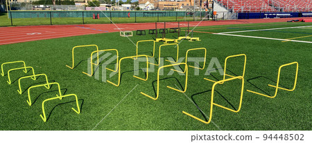 Plyo boxes pushing sleds and small mini hurdles set up on a field Plyo boxes pushing sleds and small mini hurdles set up on a field 94448502