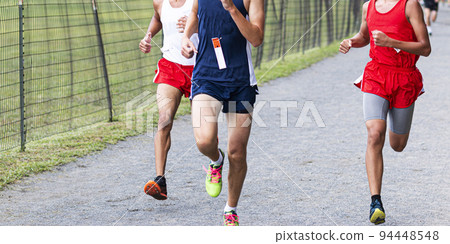 Three boys running a race down the final straightaway in a park Three boys running a race down the final straightaway in a park 94448548
