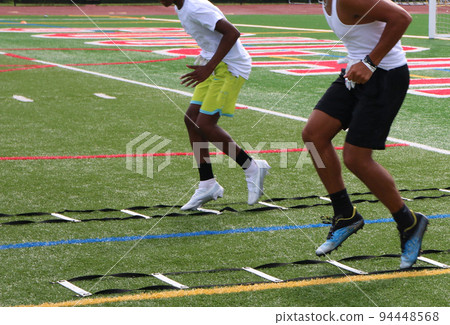 Two football players performing ladder drills during summer camp Two football players performing ladder drills during summer camp 94448568
