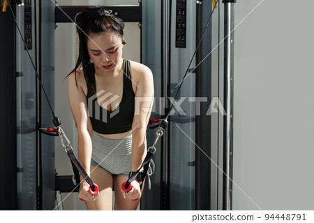 Young sportswoman doing exercise in cable crossover machine 94448791