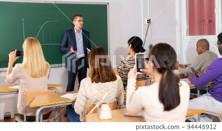 Teacher explaining new theme to adult students Teacher explaining new theme to adult students 94448912
