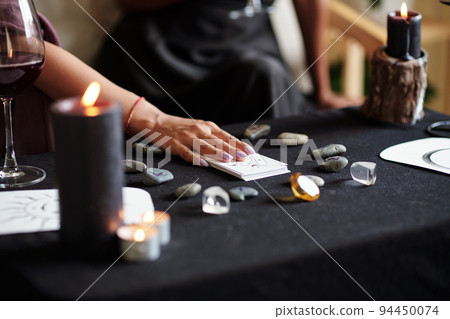 Psychic putting deck of tarot cards on table with runes 94450074
