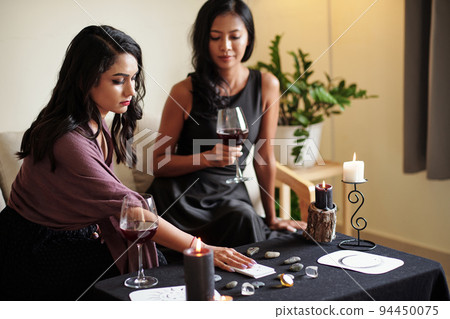 Future teller reading tarot cards for friend asking about her beloved one 94450075
