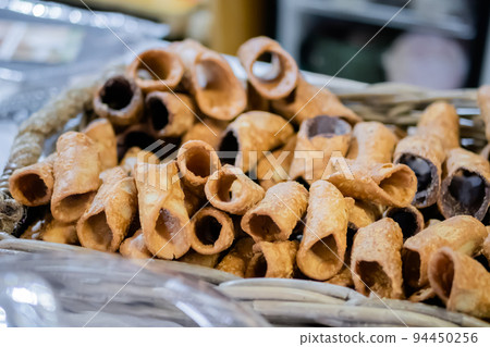 Sweet empty fried cannoli in basket on counter at food market 94450256