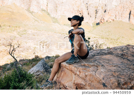 Smiling woman hiker sitting on big stone in valley enjoying the view	 94450959