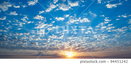 Blue sky with twilight clouds. The sun setting Blue sky with twilight clouds. The sun setting 94451242