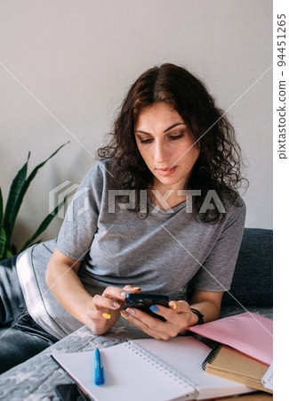 A young brunette woman is resting at home and talking on a smartphone 94451265