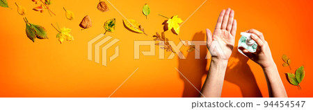 Applying sanitizer gel with autumn leaves 94454547